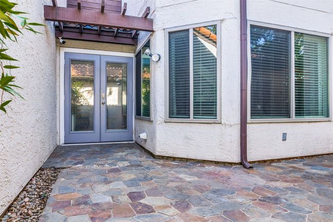 View of exterior entry featuring french doors, stucco siding, a pergola, and a patio | Image 10
