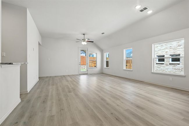 Unfurnished living room with ceiling fan, vaulted ceiling, and light wood-style floors | Image 9