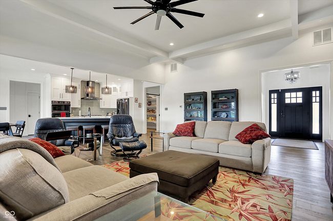 living area featuring beamed ceiling, light wood-type flooring, and visible vents | Image 7