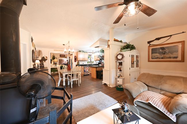 Living area with a ceiling fan, dark wood-style floors, and a chandelier | Image 19