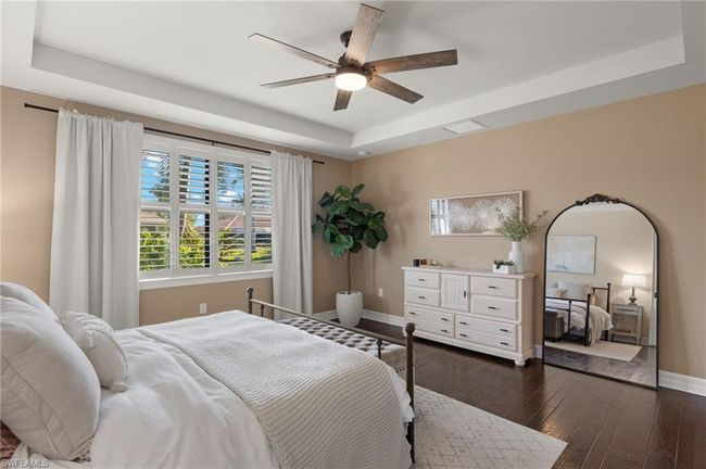 Bedroom featuring dark hardwood / wood-style flooring, a raised ceiling, and ceiling fan | Image 18