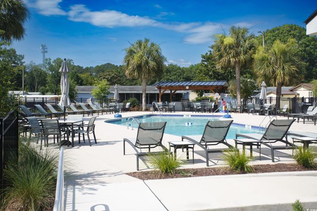 Community pool with a patio area and view of wooded area | Image 37