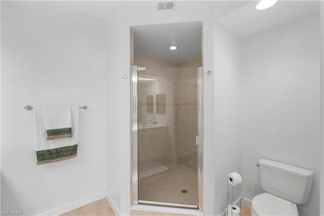 Main bathroom featuring toilet, tile patterned flooring, and a shower with shower door | Image 12