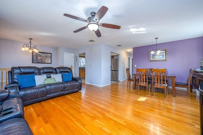 Living area with hardwood finished floors, ceiling fan with notable chandelier and baseboards | Image 10