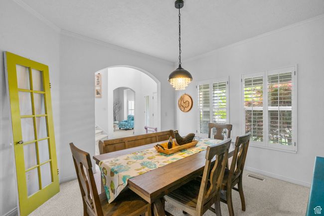 Dining space with crown molding, visible vents, baseboards, light colored carpet, and arched walkways | Image 20