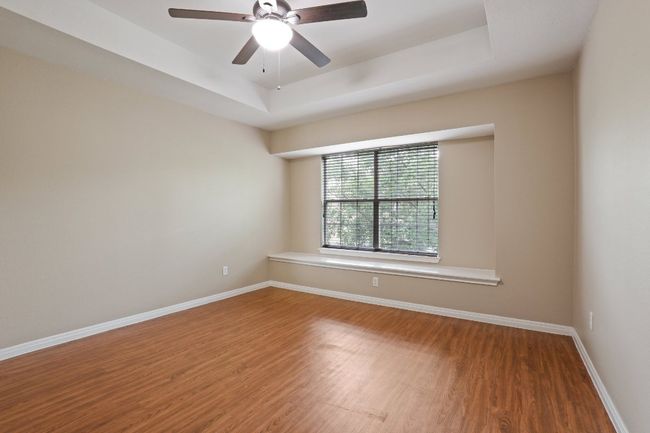 Spare room featuring a ceiling fan, baseboards, wood finished floors, and a tray ceiling | Image 25