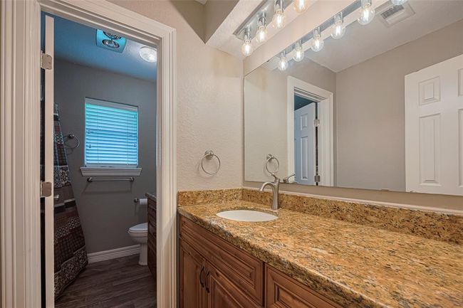 2nd bathroom features large granite vanity counters, custom lighting above large mirror, wood cabinets, and a tub/shower | Image 22