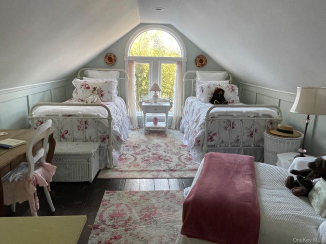 Bedroom featuring dark wood-style flooring, lofted ceiling, and a decorative wall | Image 9