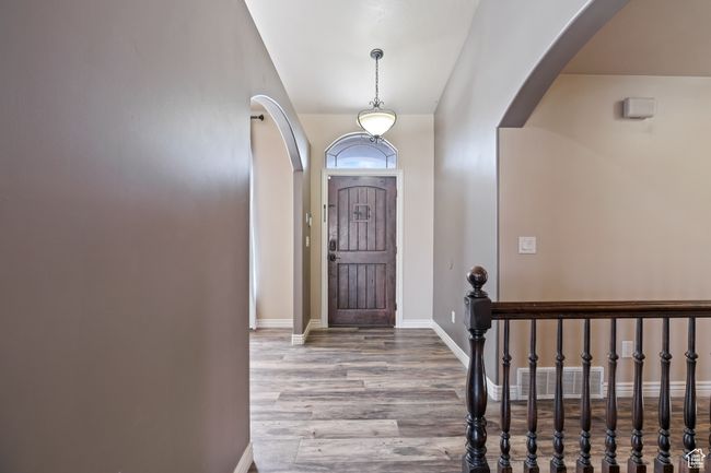 Entryway with wood finished floors, baseboards, visible vents, and arched walkways | Image 19