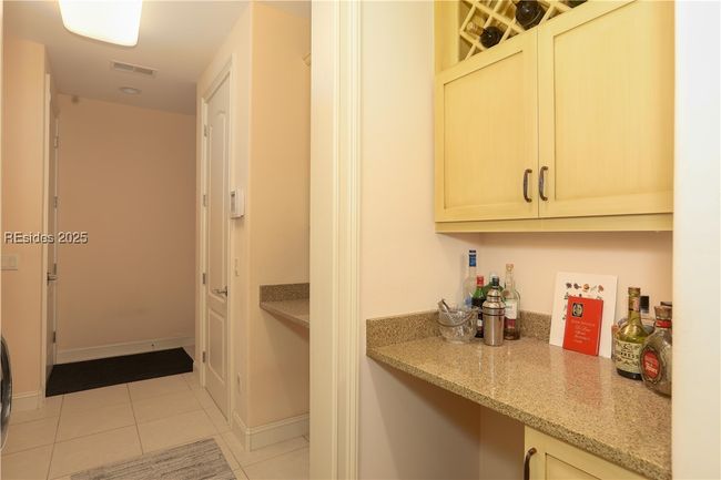 The laundry room has a bar area with room for a winecooler below, a desk or laundry folding area and a drop zone for hats with a bench to put on or take off shoes. | Image 39