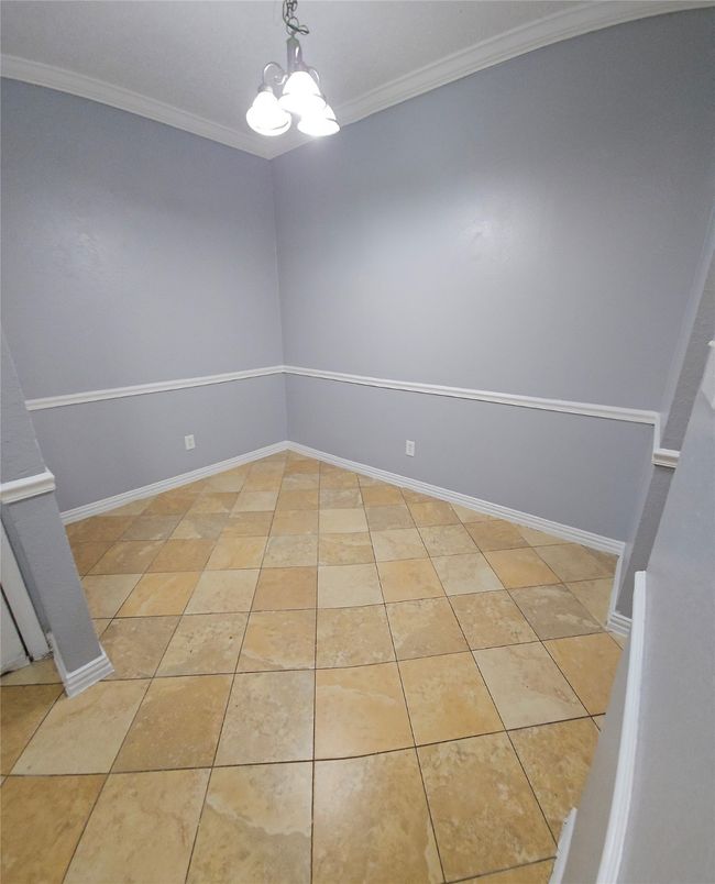 Empty room with a chandelier, crown molding, and light tile patterned flooring | Image 7