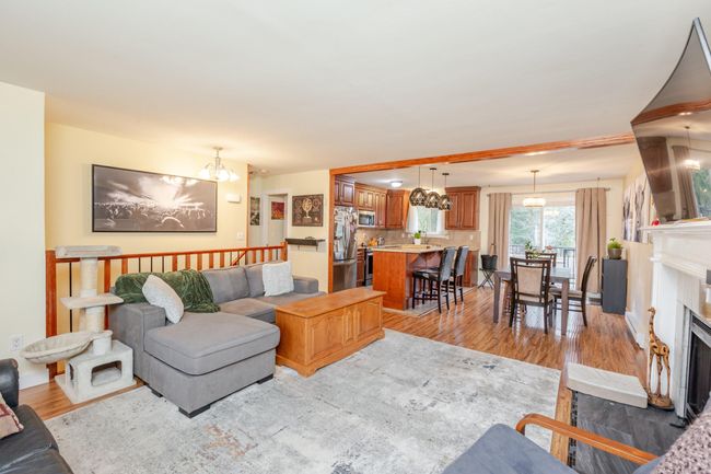 Living room with a chandelier, light wood-style floors, and a fireplace with flush hearth | Image 5