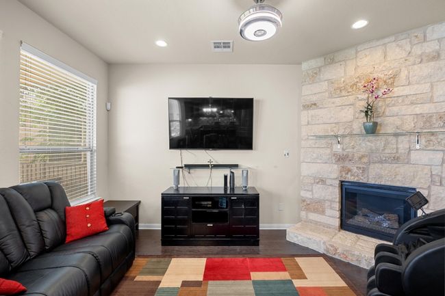 Showcasing a corner fireplace nestled in a striking stone hearth with a glass mantel plus recessed lighting so you can set your ideal atmosphere. | Image 11