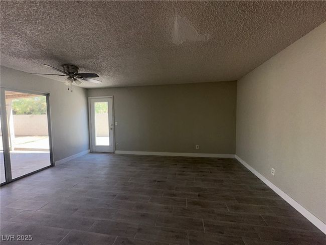 Spare room with ceiling fan, a textured ceiling, dark wood-style floors, and baseboards | Image 5