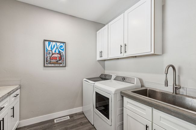 Laundry room with washer and clothes dryer, cabinet space, dark wood finished floors, and baseboards | Image 31