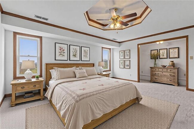 Bedroom featuring ornamental molding, a raised ceiling, visible vents, and light carpet | Image 27