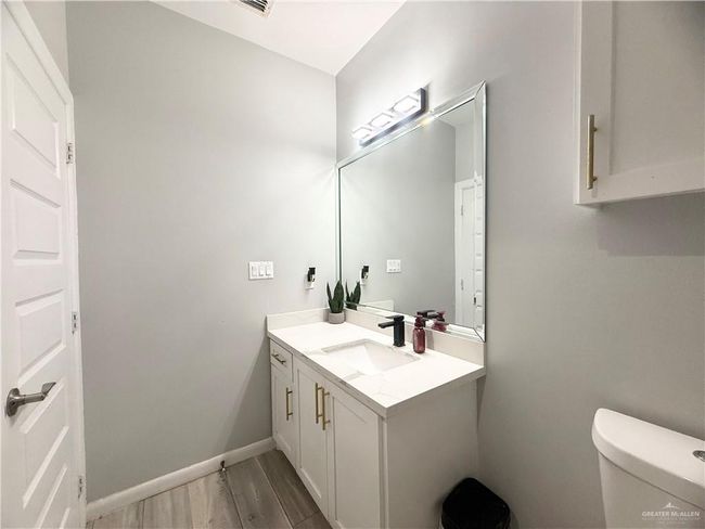 Half bath with vanity, toilet, wood finished floors, and baseboards | Image 17