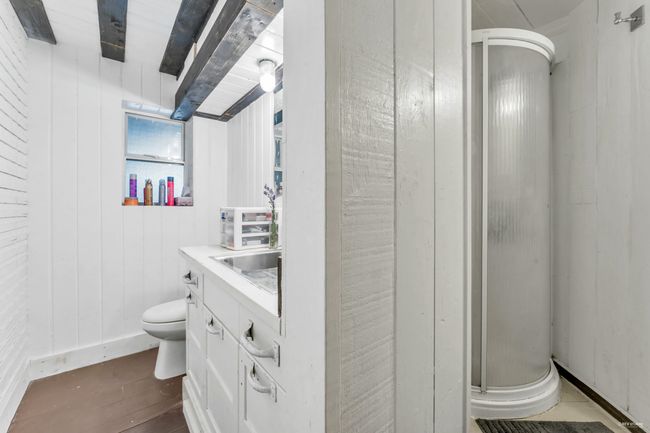 Bathroom featuring wood walls, wood finished floors, toilet, vanity, and a stall shower | Image 30