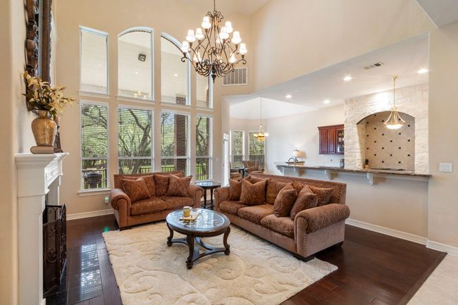 Living area featuring a chandelier, baseboards, dark wood-style flooring, and a high ceiling | Image 13