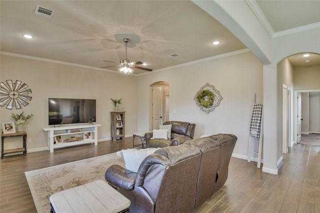 Living room featuring ceiling fan, arched walkways, and wood finished floors | Image 6
