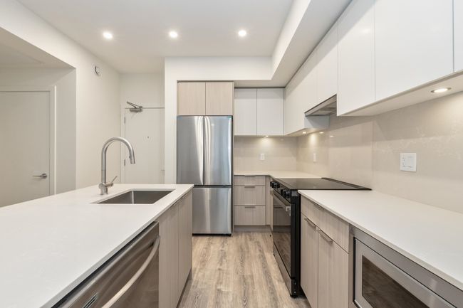 Kitchen with stainless steel appliances, a sink, modern cabinets, light countertops, and recessed lighting | Image 8