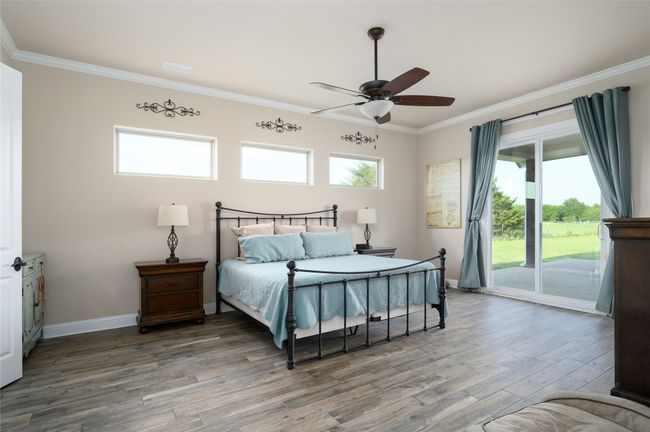 Primary Bedroom with horizontal windows, baseboards, wood finished floors, sliding door to back patio. | Image 16