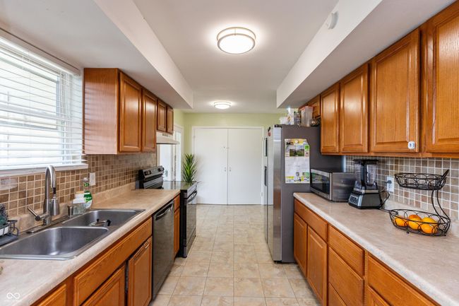 kitchen with stainless steel appliances, tasteful backsplash, brown cabinets, and light countertops | Image 9
