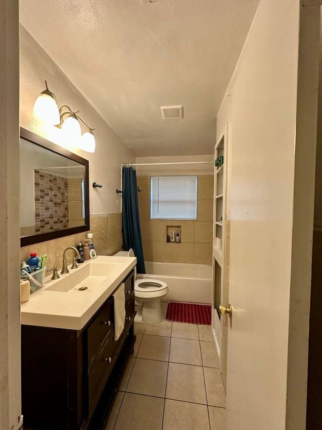 Bathroom featuring tile patterned floors, tile walls, toilet, vanity, and visible vents | Image 4