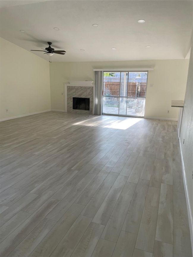 Unfurnished living room featuring baseboards, wood finished floors, ceiling fan, and a high end fireplace | Image 5