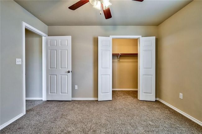 Unfurnished bedroom featuring carpet floors, a spacious closet, ceiling fan, and a closet | Image 8