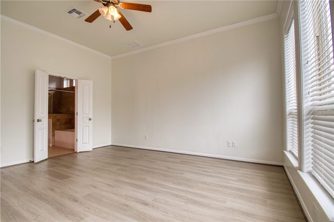 Spare room with light wood finished floors, visible vents, ornamental molding, and a ceiling fan | Image 15