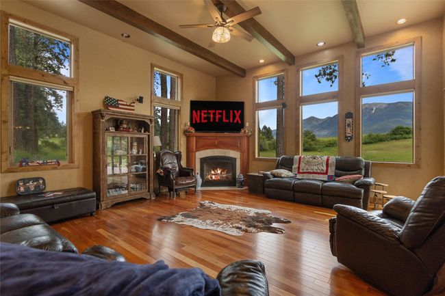 Living room with beam ceiling, a tile fireplace, ceiling fan, hardwood / wood-style flooring, and healthy amount of natural light | Image 9