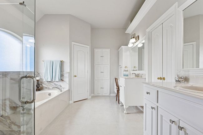 Full bathroom with two vanities, a garden tub, a shower stall, tile patterned flooring, and a closet | Image 21