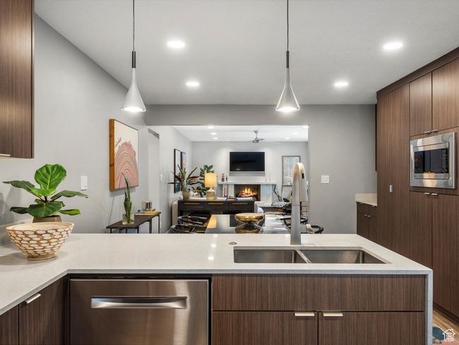 Kitchen with stainless steel appliances, a warm lit fireplace, decorative light fixtures, recessed lighting, and modern cabinets | Image 15
