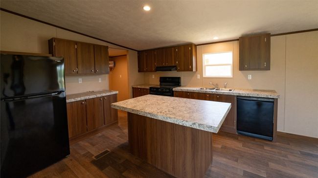 Kitchen with black appliances, ventilation hood, light countertops, dark wood-style floors, and lofted ceiling | Image 27