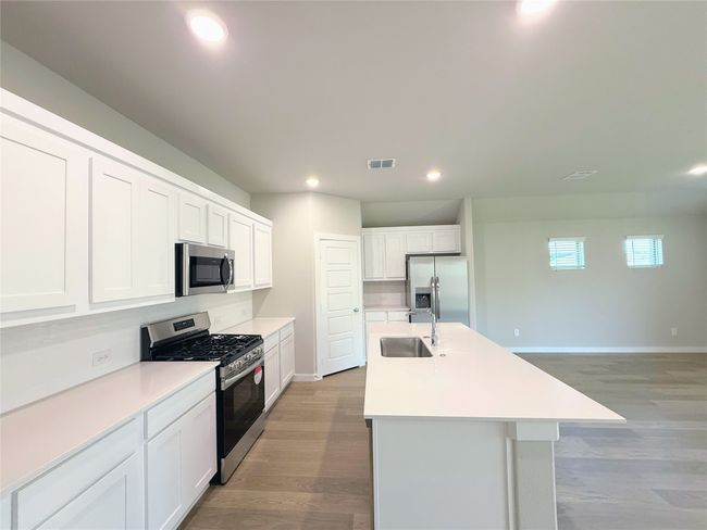 Kitchen with appliances with stainless steel finishes, light wood-style floors, an island with sink, recessed lighting, and backsplash | Image 7