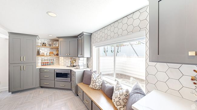 Kitchen featuring stainless steel microwave, gray cabinets, tasteful backsplash, and open shelves | Image 22