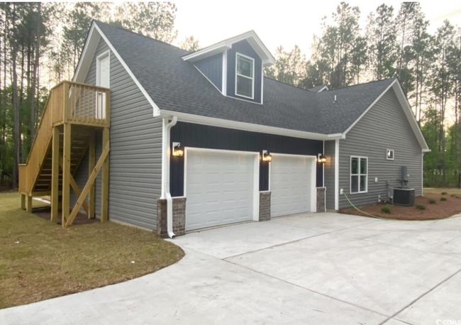 View of side of home with concrete driveway, a garage, roof with shingles, and stairway | Image 5