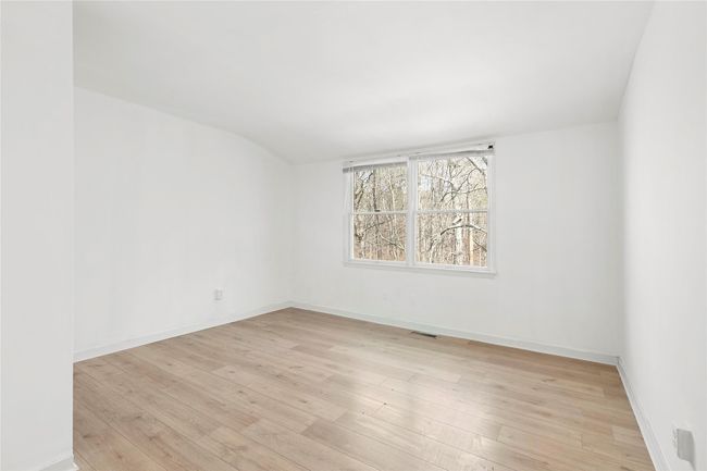 Empty room with light wood finished floors, visible vents, baseboards, and vaulted ceiling | Image 9