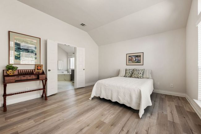 Bedroom featuring visible vents, ensuite bathroom, wood finished floors, baseboards, and vaulted ceiling | Image 19