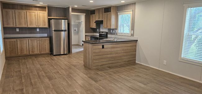 Kitchen featuring stainless steel appliances, dark countertops, decorative backsplash, wood finished floors, and recessed lighting | Image 15