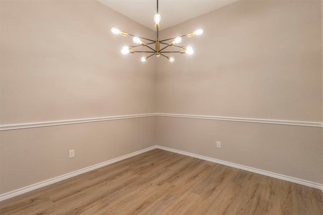 Empty room with baseboards, an inviting chandelier, and light wood-type flooring | Image 11
