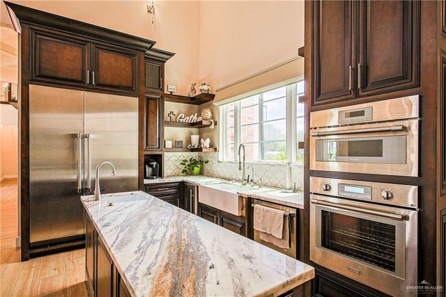 Kitchen featuring appliances with stainless steel finishes, porcelain flooring, brazilian countertops, decorative backsplash, and a vegetable sink prep island | Image 20