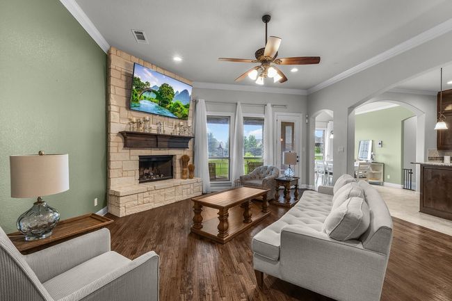 Living area featuring arched walkways, a fireplace, ceiling fan, crown molding, and wood finished floors | Image 8