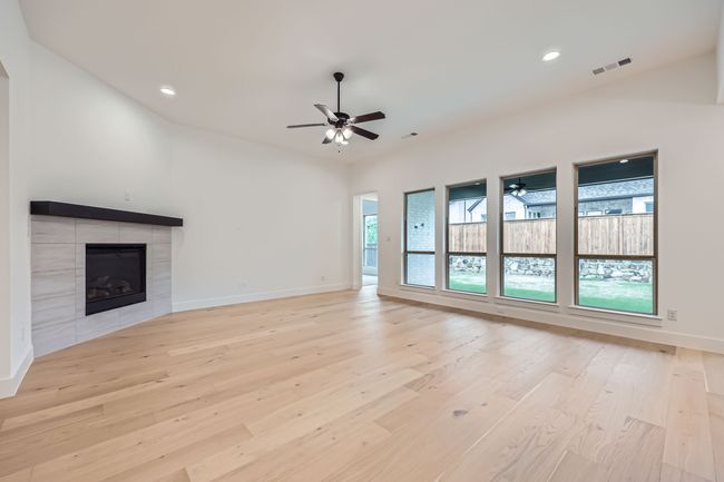 Unfurnished living room with a ceiling fan, light wood finished floors, and visible vents | Image 6
