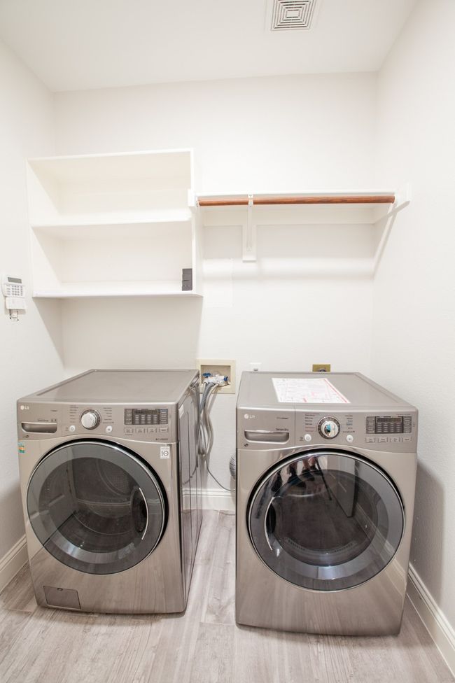 Laundry area featuring washing machine and clothes dryer and light wood finished floors | Image 23