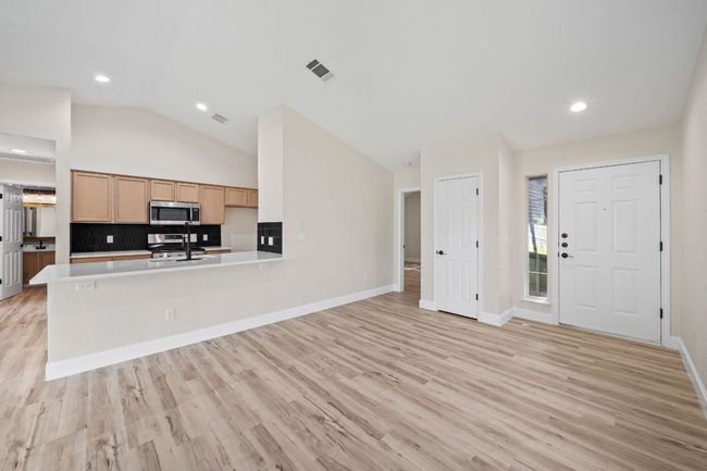 Kitchen featuring stainless steel microwave, light countertops, backsplash, light wood-type flooring, and stove | Image 7