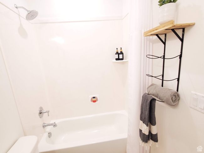Full bath featuring toilet, shower / tub combo, baseboards, and wood finished floors | Image 12