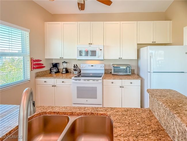 Kitchen featuring a toaster, white appliances, a sink, a ceiling fan, and white cabinetry | Image 16