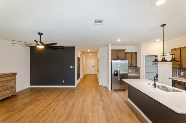 Kitchen with stainless steel fridge with ice dispenser, a sink, light wood finished floors, decorative backsplash, and recessed lighting | Image 10